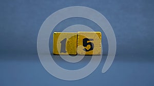 Wooden block with number 15. Yellow color on dark background