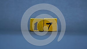 Wooden block with number 17. Yellow color on dark background