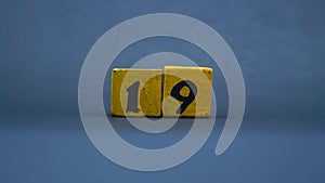 Wooden block with number 19. Yellow color on dark background