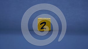 Wooden block with number 2. Yellow color on dark background