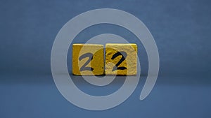 Wooden block with number 22. Yellow color on dark background