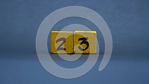 Wooden block with number 23. Yellow color on dark background