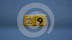 Wooden block with number 29. Yellow color on dark background