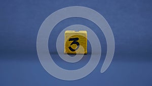 Wooden block with number 3. Yellow color on dark background