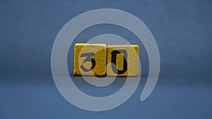 Wooden block with number 30. Yellow color on dark background