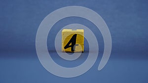 Wooden block with number 4. Yellow color on dark background