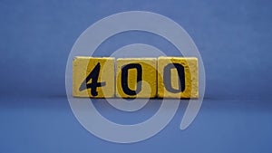 Wooden block with number 400. Yellow color on dark background