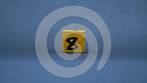 Wooden block with number 8. Yellow color on dark background