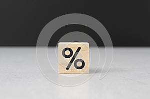 Wooden block percent per cent sign on cement table black background wood cube concept, symbol used to indicate a percentage