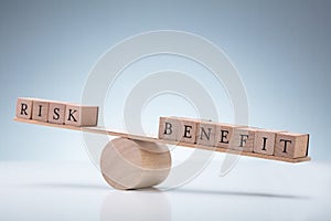 Wooden Block With Risk And Benefit Wooden Block On Seesaw