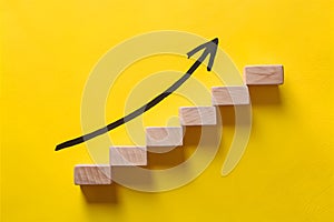 Wooden block stairs on yellow backdrop with black arrow, representing growth and progress