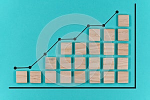 Wooden block statistics histogram with graph showing growth trend on blue paper background