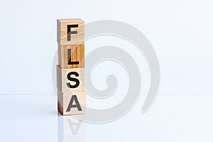 Wooden block with words FLSA - acronim FLSA - Fair Labor Standards Act