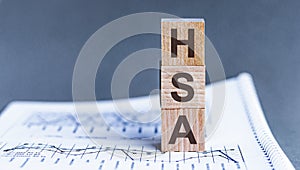 Wooden block with words HSA - acronim HSA - Health Savings Account. . HSA Health Savings Account Wooden Blocks on Grey background