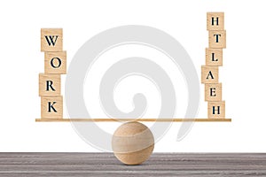 Wooden block with words work and health on wooden seesaw balancing on wood desk and white background