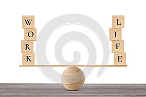 Wooden block with words work and life on wooden seesaw balancing on wood desk and white background
