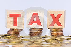 Wooden block with written word Tax on stacked gold coins