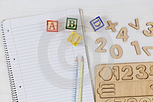 Wooden blocks with ABC letters, open notepad, numbers on wooden table. Games and tools for kids in preschool or daycare. Education