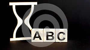 Wooden blocks ABC with wooden sand clock on table. Personal, career or business development, mindset concept