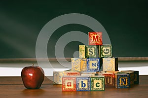 Wooden blocks and apple on desk