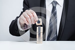 Wooden blocks with black arrow icon, hand in suit holding cube on white background, business profit success concept