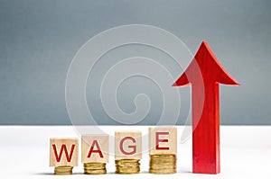 Wooden blocks with coins and the word Wage and up arrow. Increase of salary. Wage rates. Career growth. Increase profits and