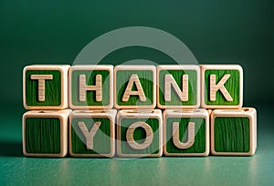 Wooden blocks cubes stacked to form the words THANK YOU in green
