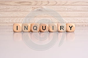 wooden blocks displaying the word 'Inquiry' arranged on a glossy gray surface