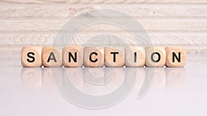 wooden blocks displaying the word 'SANCTION' arranged on a glossy gray surface photo