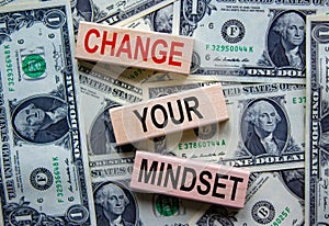 Wooden blocks form the text `change your mindset` on beautiful background from dollar bills. Concept