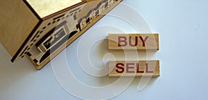 Wooden blocks form the words `buy sell` near miniature house