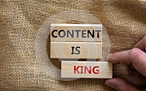 Wooden blocks form the words `content is king` on canvas background. Male hand. Business concept
