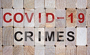 Wooden blocks form the words `covid-19 crimes`. Beautiful wooden background