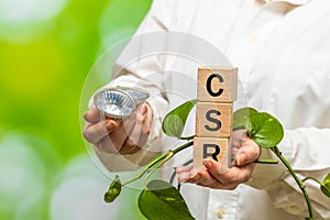 wooden blocks held in hand with the word CSR, concept, for business and organization, corporate social responsibility and communit