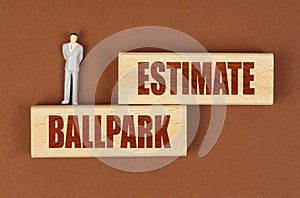 On wooden blocks with the inscription - BALLPARK ESTIMATE, there is a miniature figure of a businessman.