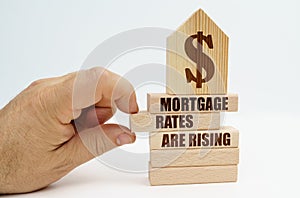 On wooden blocks with the inscription - Mortgage rates are rising, there is a model of the house.