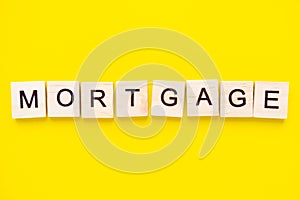 Wooden blocks with the lettering word mortgage on top of yellow background. business and finance concept.