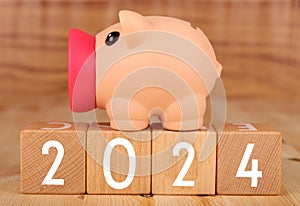 Wooden blocks lined up with the letters 2024 with piggy bank concept of saving