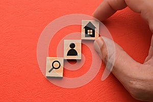 Wooden blocks with magnifying glass, people and home icons. House search, buying and selling real estate concept