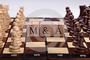 Wooden Blocks With Mergers And Acquisitions Text On Chess Board photo