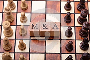 Wooden Blocks With Mergers And Acquisitions Text On Chess Board photo