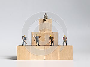 Wooden blocks and miniature people. The concept of unequal social structure.