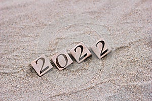 Wooden blocks with the numbers 2022 are located on the sand on the beach