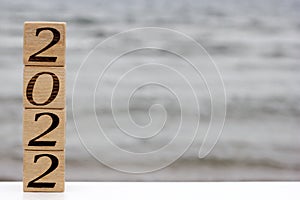 Wooden blocks with the numbers 2022 are standing on the top of each other like a pyramid