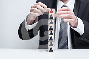 Wooden blocks with people icons and businessman hands in black suit, leadership, carieer, business concept