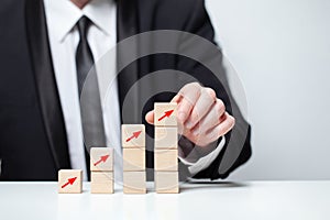 Wooden blocks with red arrows icons, businessman in suit hand holding cube, business profit success concept