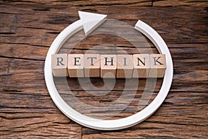 Wooden Blocks With Rethink Word And Arrow Over Wooden Surface photo