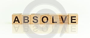 Wooden Blocks with the text: Absolve. The text is written in black letters and is reflected in the mirror surface of the table