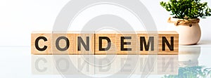 Wooden Blocks with the text: condemn. The text is written in black letters and is reflected in the mirror surface of the table photo