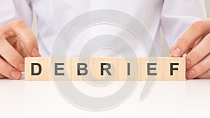 wooden blocks with text Debrief on the cardboard background. concept photo